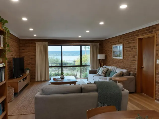 Living room with recessed downlights, brick walls and large window overlooking water in Copacabana