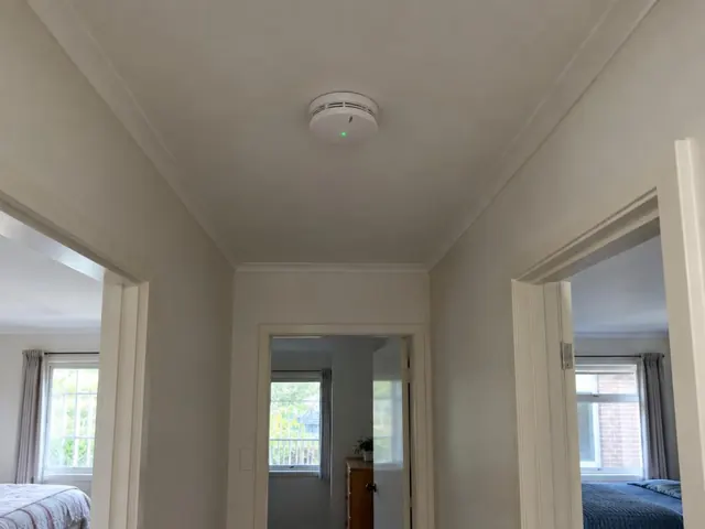 Ceiling smoke alarm in a hallway with doorways and bedrooms visible in Terrigal